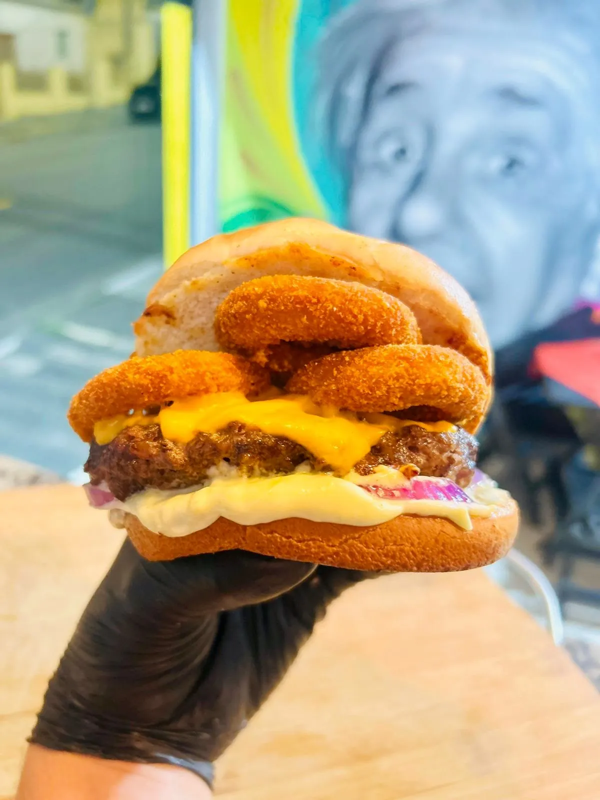 Hambúrguer coberto por anéis de cebola empanados e cheddar