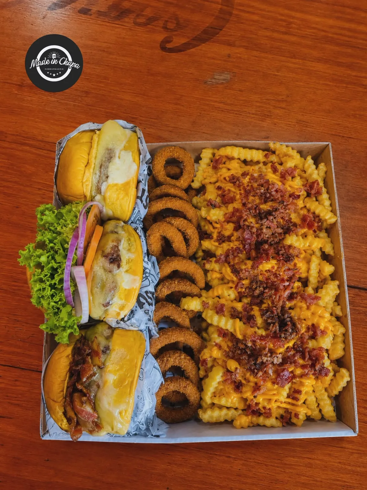 Bandeja com três hambúrgueres, batata com cheddar e anéis de cebola
